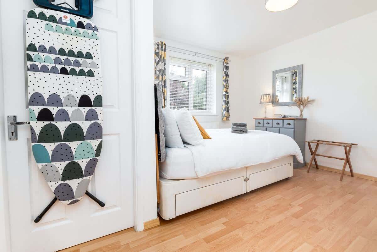 A bedroom with a bed, a dresser, a mirror, and a door with a patterned curtain.
