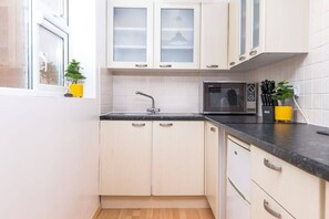 A kitchen with white cabinets, a black countertop, a microwave, and a sink. - Inviting and Cosy Annexe | Free Parking and Wi-Fi (Nottingham)