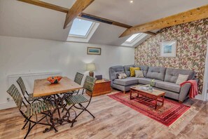Ein gemütliches Wohnzimmer mit Holztisch, einer Couch und einer Wand mit Muster.