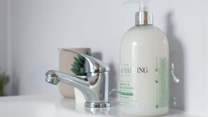 A bathroom with a modern faucet and a bottle of hand wash soap.