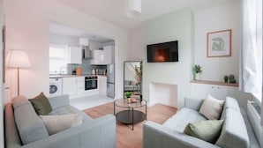 A modern living room with grey sofas, a coffee table, and a TV mounted on the wall.