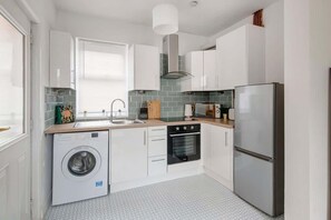Una cucina compatta con lavatrice, forno e frigorifero.
