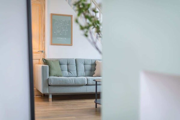 A room with a light grey sofa, a small table, and a framed picture on the wall.