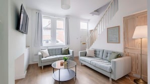 A modern living room with two sofas, a coffee table, and a TV mounted on the wall.