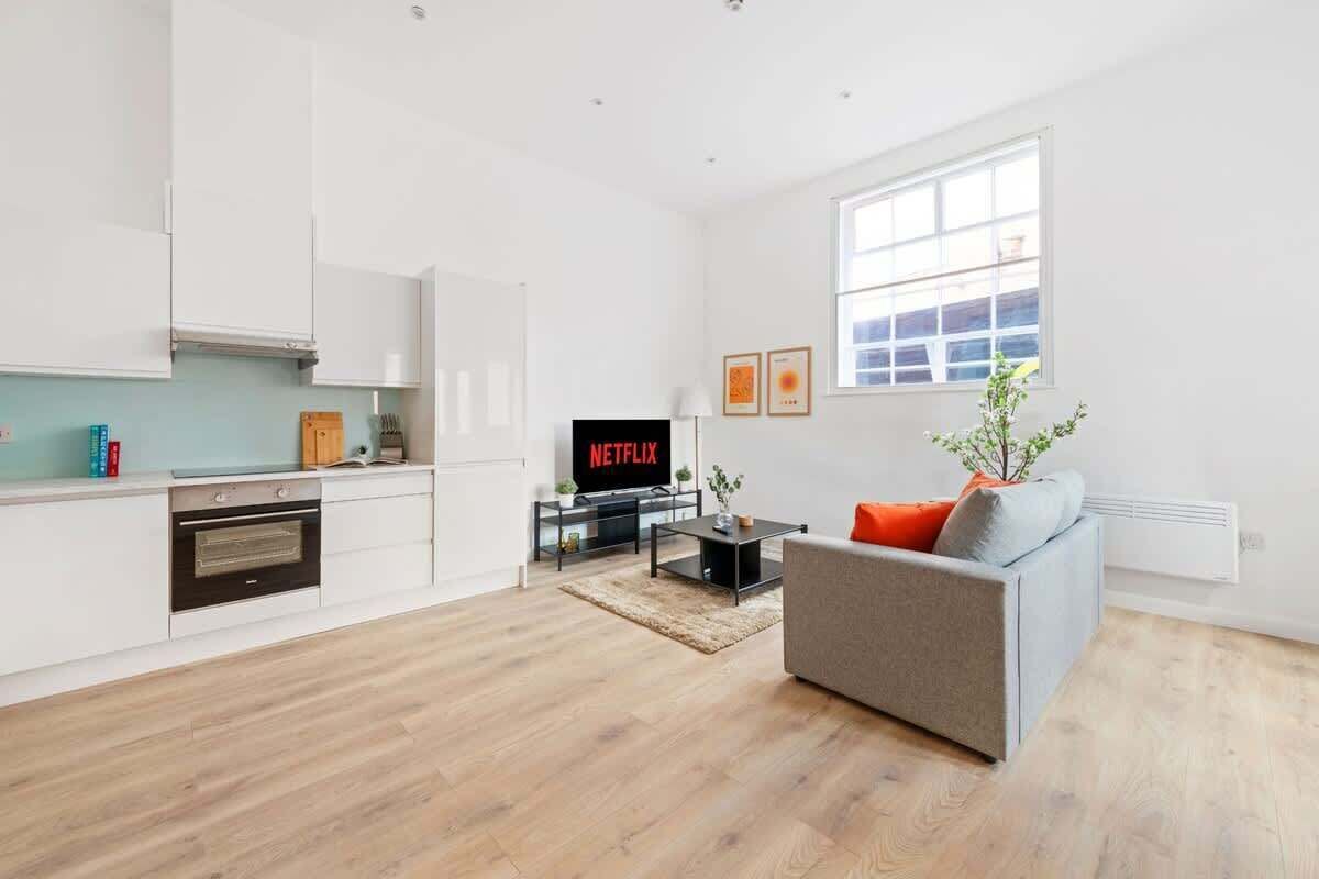 A modern living room with a grey sofa, a coffee table, and a TV displaying 'NETFLIX'.