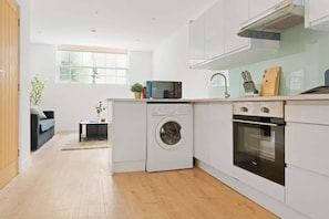 A modern kitchen with a washing machine, oven, and microwave.