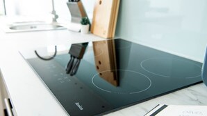Een moderne keuken met een inductiekookplaat, een houten snijplank en een kookboek op het aanrecht.