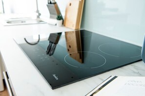 A modern kitchen with an induction cooktop, a wooden cutting board, and a cookbook on the counter.