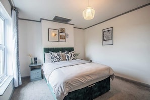 Een slaapkamer met een bed, nachtkastje en wanddecoratie.