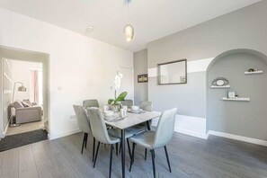 Een eetruimte met een tafel voor vier personen, een potplant en een moderne lamp.