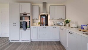 Una cucina moderna con mobili bianchi, forno integrato, microonde e tostapane.