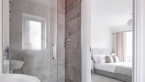 Un bagno moderno con box doccia in vetro, lavandino bianco e doccetta a vista.