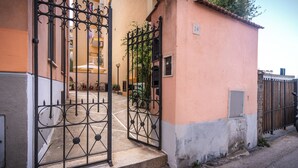 A gated entrance to a building with a pink facade and a metal gate. - Brand new Central Sorrento 2 BR 2 BT Flat AC Wifi Parking Balcony (Sorrento)