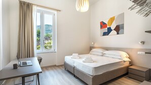 A modern hotel room with a bed, a desk with a laptop, a bedside table, and a window with curtains. - Brand new Central Sorrento 2 BR 2 BT Flat AC Wifi Parking Balcony (Sorrento)