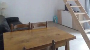 Ein Zimmer mit Holztisch und -stühlen, einer weißen Treppe und einem weißen Geländer.