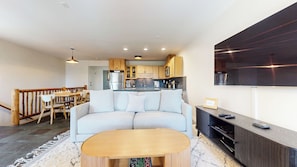 A modern living room with a sofa, a wooden coffee table, and a TV mounted on the wall. - Updated 2-Story Home, Great Views, Steam Shower & Washer/Dryer, Near Village (Mammoth Lakes)