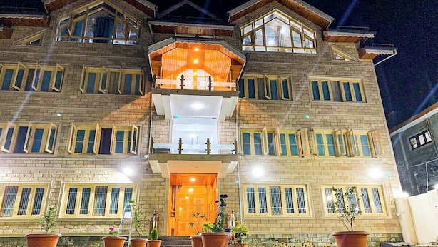 A multi-story building with a prominent entrance, large windows, and a balcony with lighting. - Arbiya Villa (Srinagar)