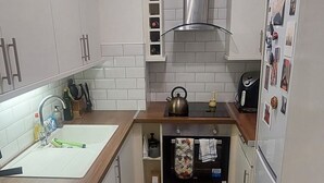 A compact kitchen with white cabinets, a stainless steel range hood, a sink, and a refrigerator. - Stylish, Comfy 1BD with Cathedral Neighbour (Dublin)