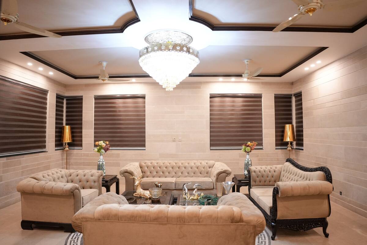 Un salon luxueux agrémenté d’un grand lustre, d’un ensemble de canapés beige et d’objets décoratifs disposés sur une table basse.