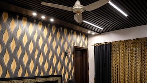 A modern bedroom with a large bed, a ceiling fan, and a patterned wall. - Triphatch Farm House (Lahore)