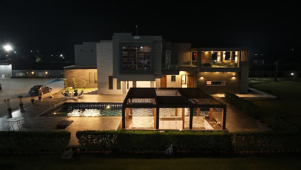 A modern two-story house with a swimming pool, outdoor seating, and a covered patio area. - Triphatch Farm House (Lahore)