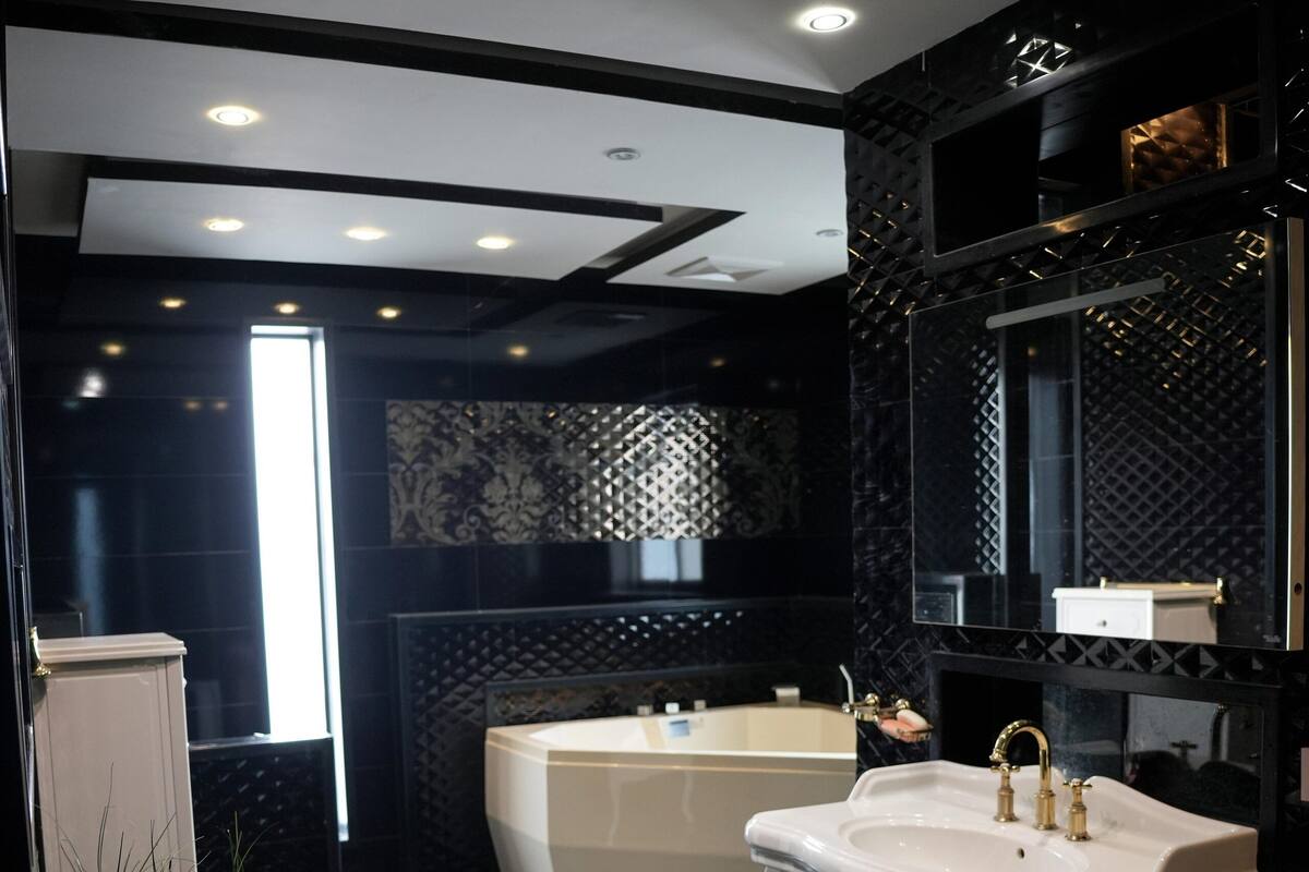 Une salle de bain moderne avec un lavabo blanc, une baignoire et un grand miroir.
