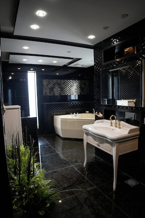 Un baño moderno con un lavamanos blanco, una bañera y un espejo grande.
