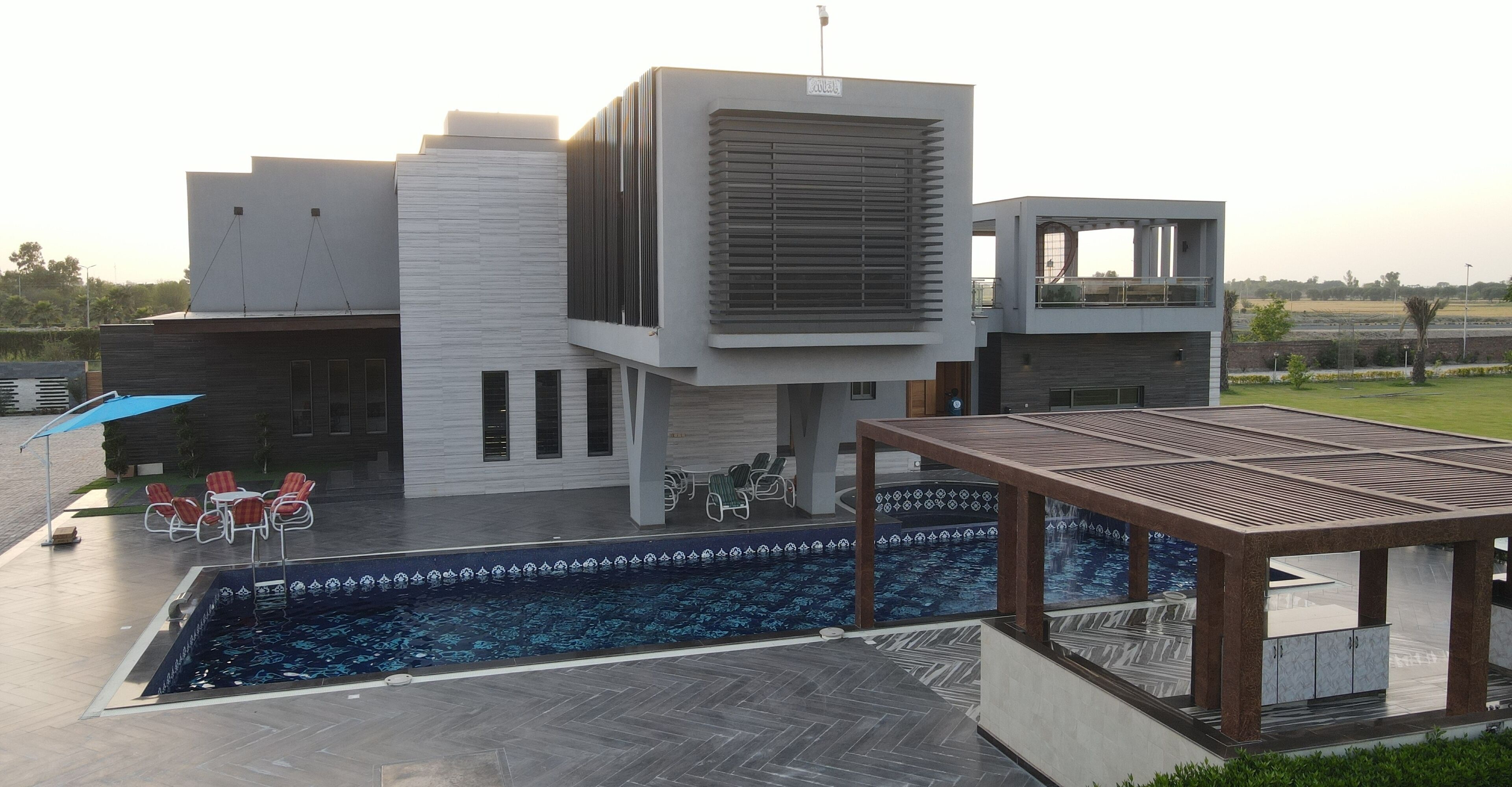 A modern building with a swimming pool, outdoor seating, and a covered area.