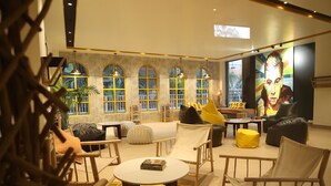 Un espace de détente moderne doté de grandes fenêtres en arc de cercle, de sièges confortables et d’une grande fresque murale.