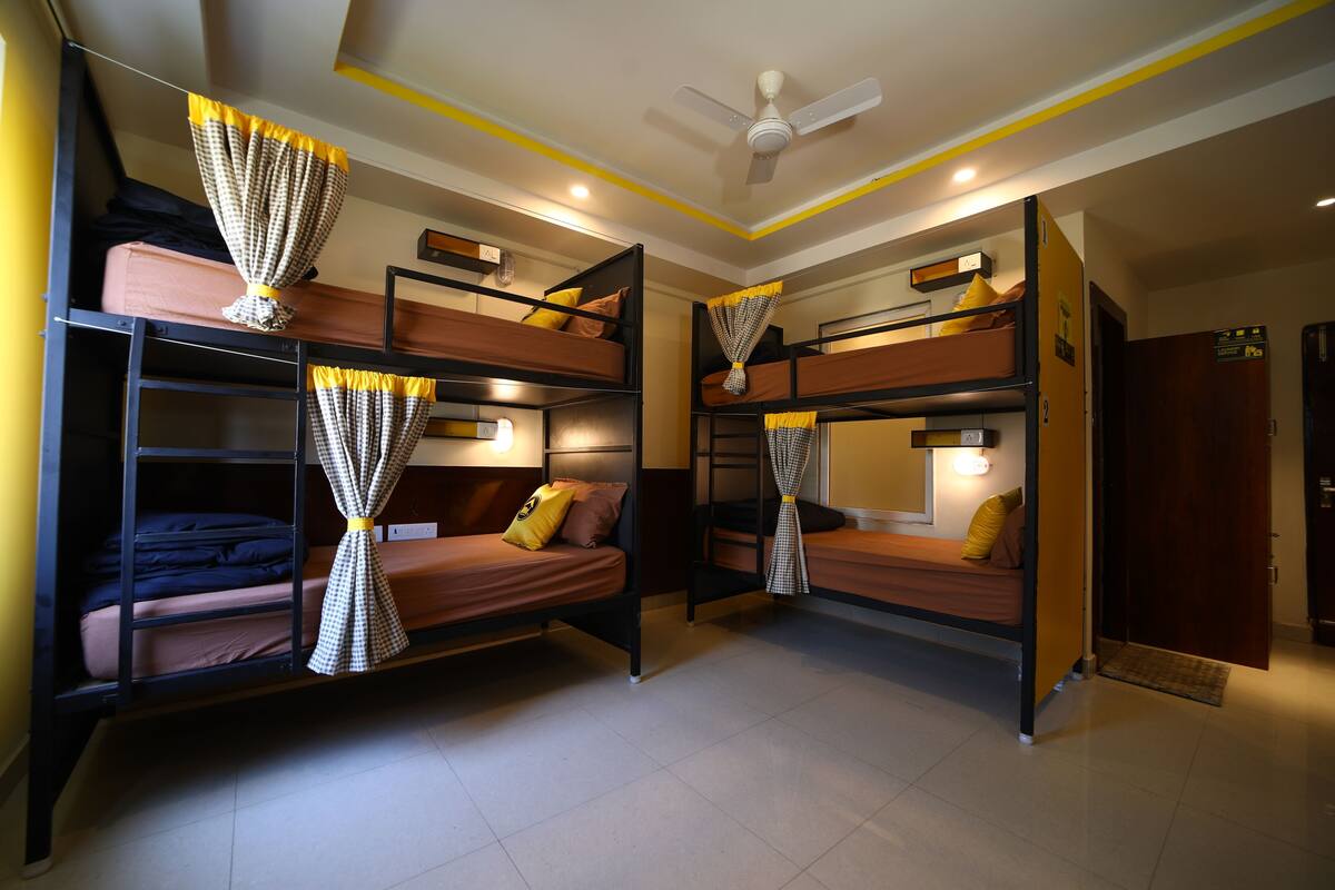 A dormitory room with bunk beds, a ceiling fan, and a door.