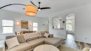 A modern living room with a sectional sofa, a round coffee table, and a ceiling fan.