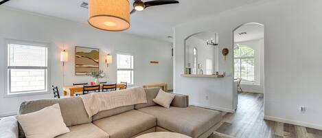 A modern living room with a sectional sofa, a round coffee table, and a ceiling fan.