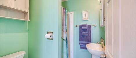 Une salle de bain équipée de toilettes, d’un lavabo, d’un rideau de douche et d’un porte-serviettes.