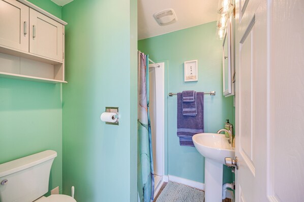 A bathroom with a toilet, a sink, a shower curtain, and a towel rack.