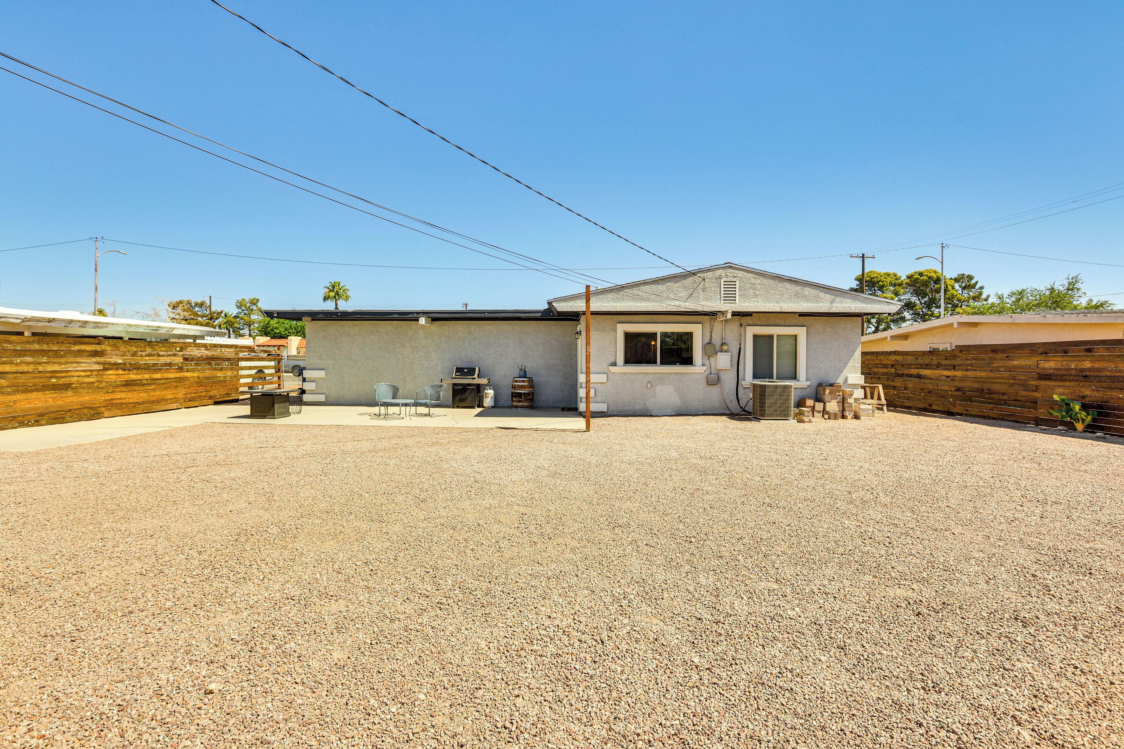 A single-story house with a gravel driveway, a small patio area with outdoor furniture, and a wooden fence surrounding the property.