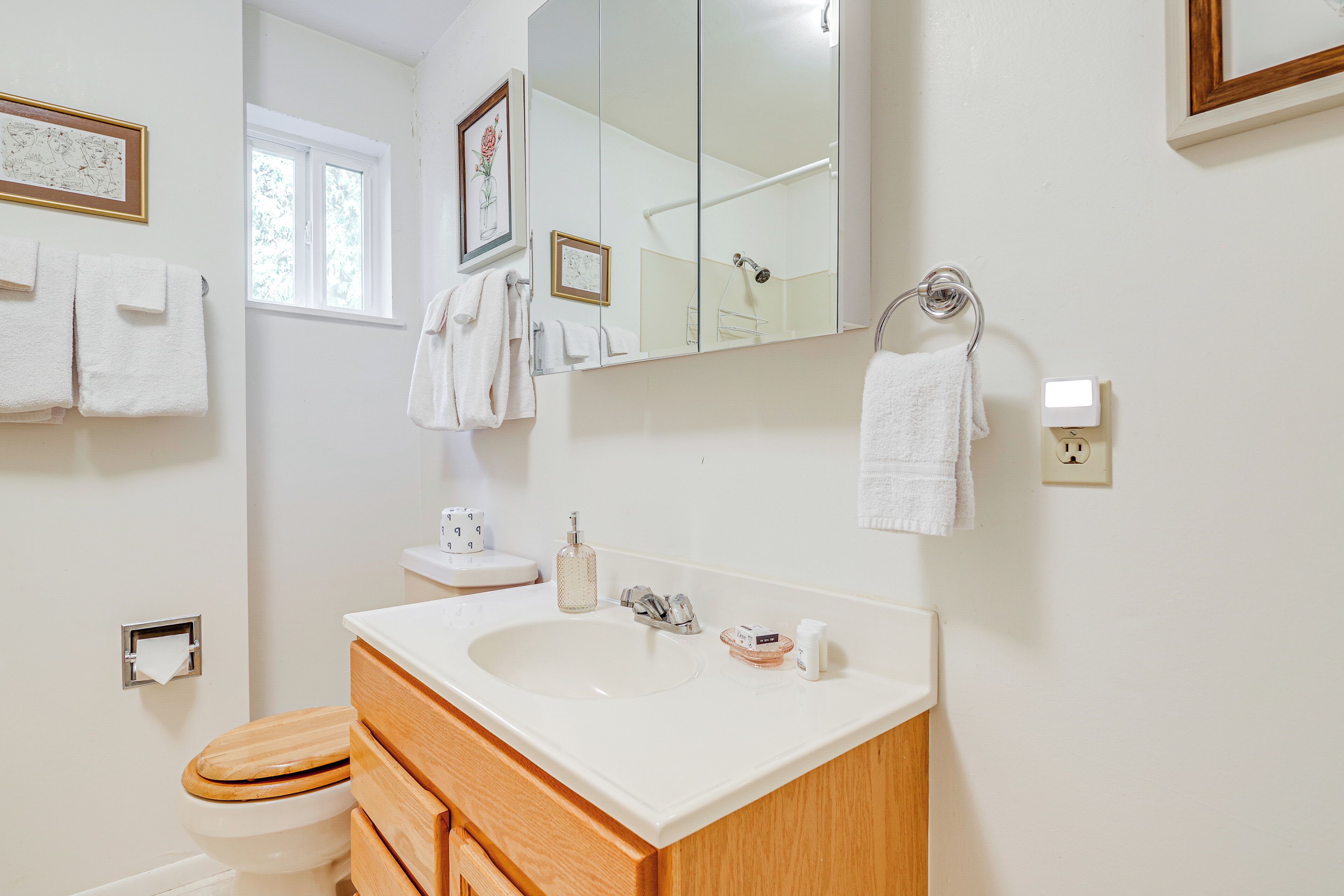 A bathroom with a white sink, wooden vanity, and a large mirror.