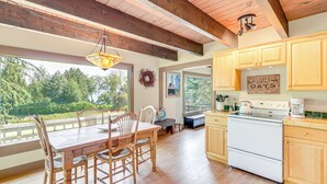 A spacious kitchen with wooden cabinets, a white stove, and a dining area with a wooden table and chairs.