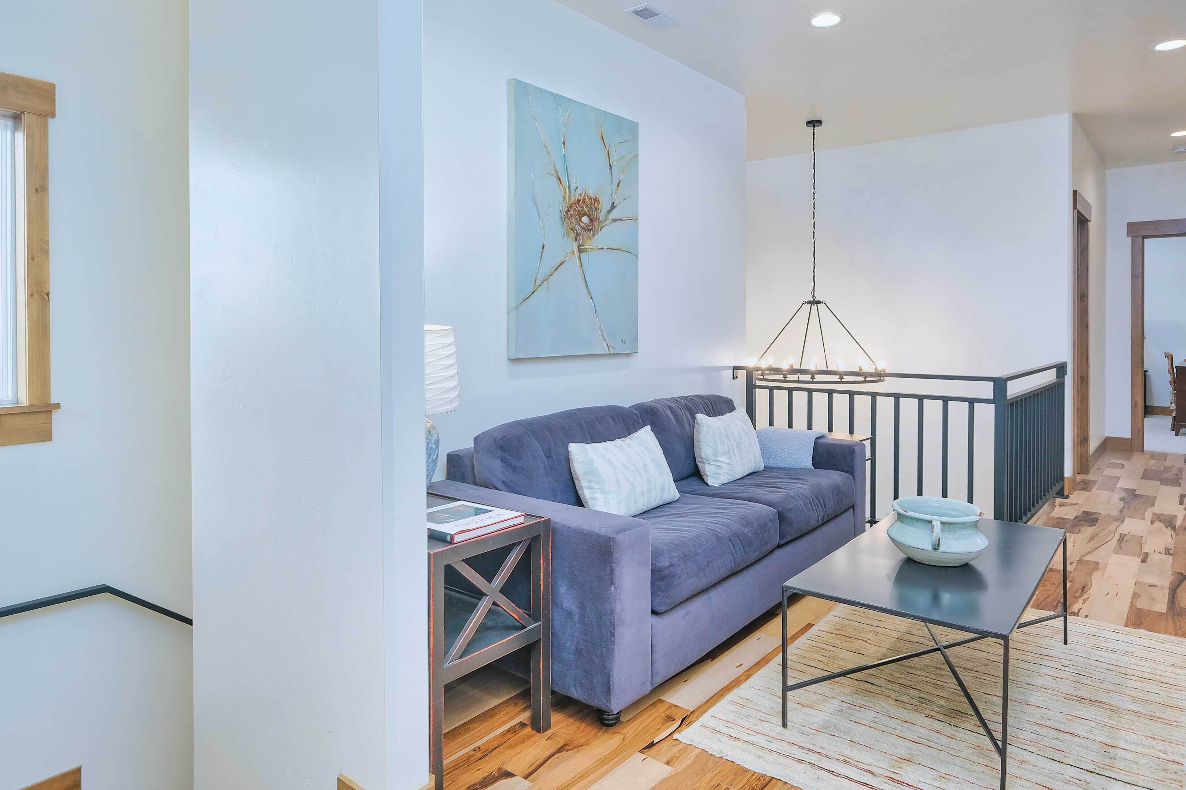 A modern living room with a sofa, a coffee table, and a painting on the wall.