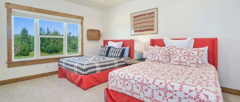 A bedroom with two beds, a large window, and a view of greenery.