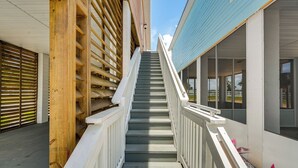 Un escalier avec des rampes blanches mène à un bâtiment à la façade bleue.