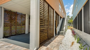 Un bâtiment moderne doté d’un parking couvert, d’un escalier et d’un chemin bordé de plantes.