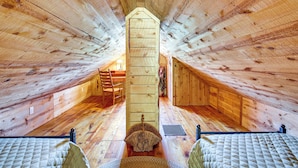 A wooden attic bedroom with a sloped ceiling, a bed, a chair, and a small window. - Remote Custer Cabin w/ Fire Pit & Near State Park! (Custer)