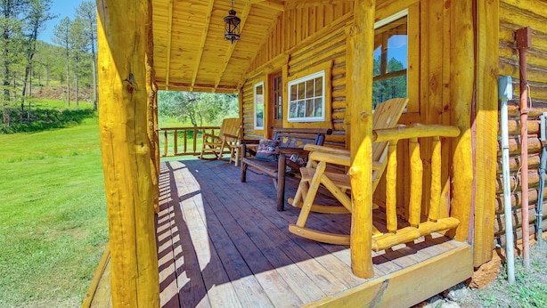 A wooden cabin with a porch, rocking chairs, and a view of the surrounding forest. - Remote Custer Cabin w/ Fire Pit & Near State Park! (Custer)
