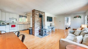 A spacious living area with a fireplace, a dining table, and a sofa. - Becket Home w/ 3-season Porch: Walk to Lake Access (Becket)