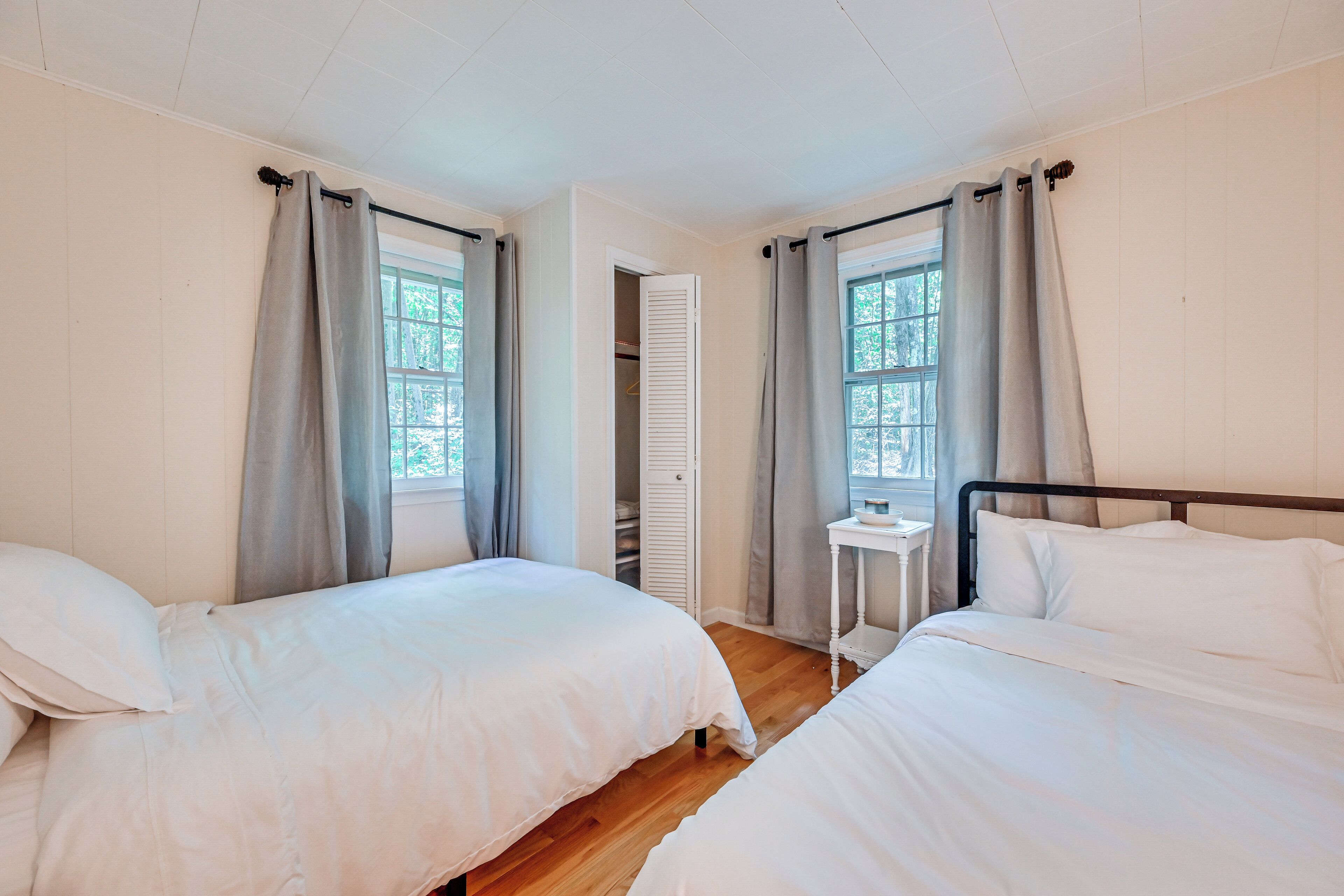A room with two beds, a small table, and a window with curtains.