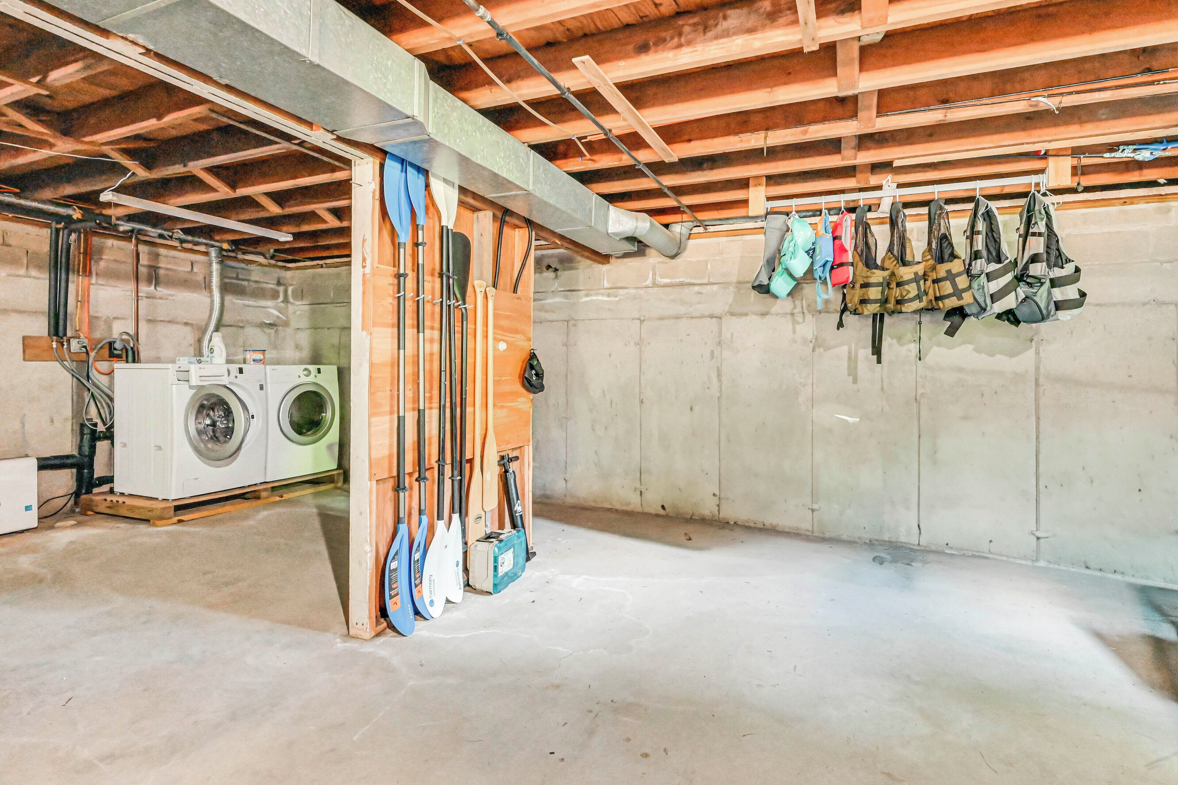 A basement with a washing machine, wooden beams, and various paddles and gear hanging on the wall.