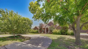 A residential area with a curved driveway leading to a brick house with a gabled roof. - Sunny Stephenville Home w/ Pool: 4 Mi to Downtown (Stephenville)
