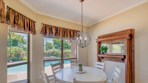 A dining area with a round table, white chairs, a hanging light fixture, and a view of a swimming pool. - Sunny Stephenville Home w/ Pool: 4 Mi to Downtown (Stephenville)