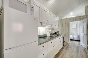 Una cocina moderna con armarios blancos, estufa integrada y un lavamanos.