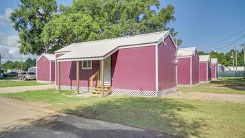 A row of red mobile homes with white trim and a small porch area.